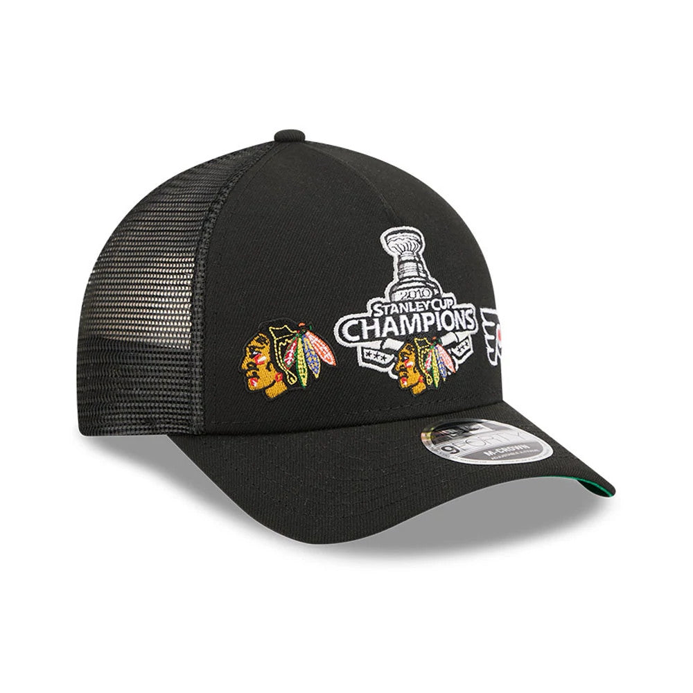 Blackhawks NHL Stanley Cup Black New Era 9FORTY M-Crown A-Frame Trucker Adjustable Cap, three-quarter view showing the Stanley Cup Champions embroidered logo centred on the front panels with two colourful Blackhawks logos.