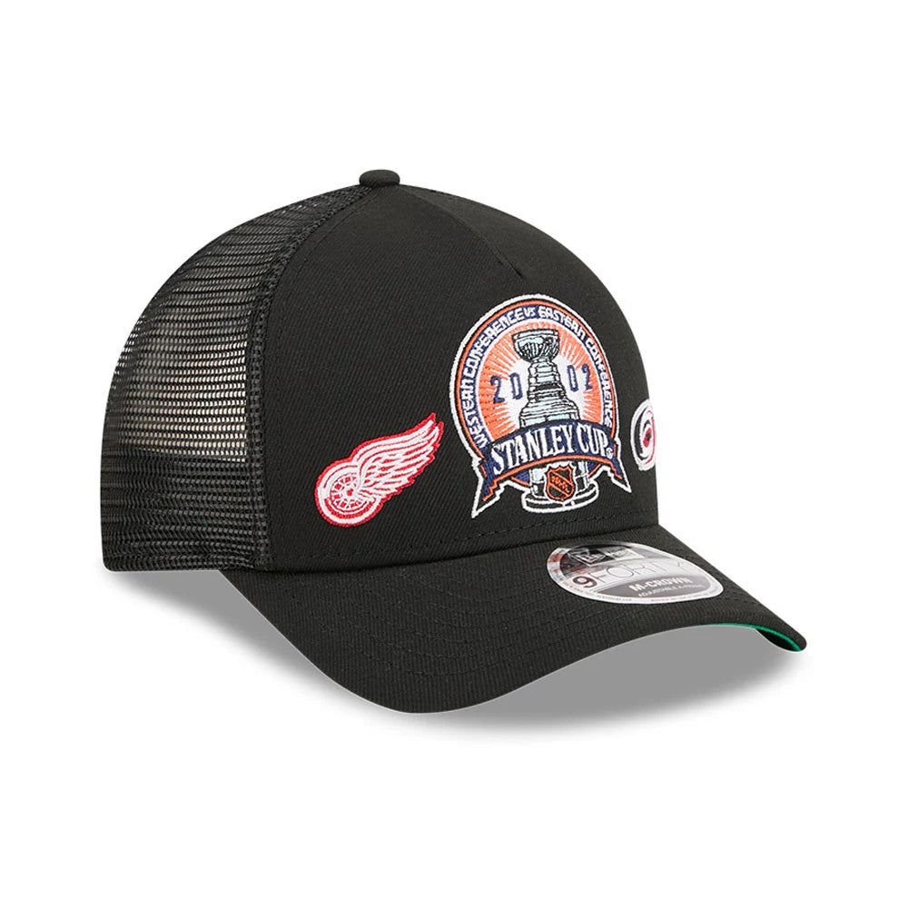 Red Wings NHL Stanley Cup Black New Era 9FORTY M-Crown A-Frame Trucker Adjustable Cap, three-quarter view showing a large embroidered Stanley Cup patch on the front panel, red Wings logo on the left, and a 9FORTY size sticker on the curved visor.
