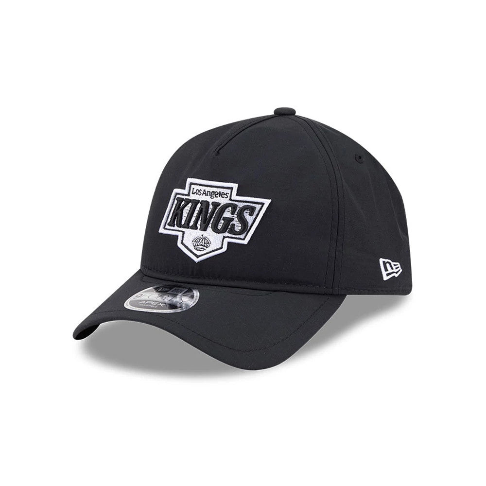 Kings NHL Quickstrike Black New Era 9FORTY Apex Adjustable Cap, three-quarter view showing the raised embroidered Kings logo on the front panel, a black curved visor with a 9FORTY size sticker, and a white New Era flag logo on the left side.