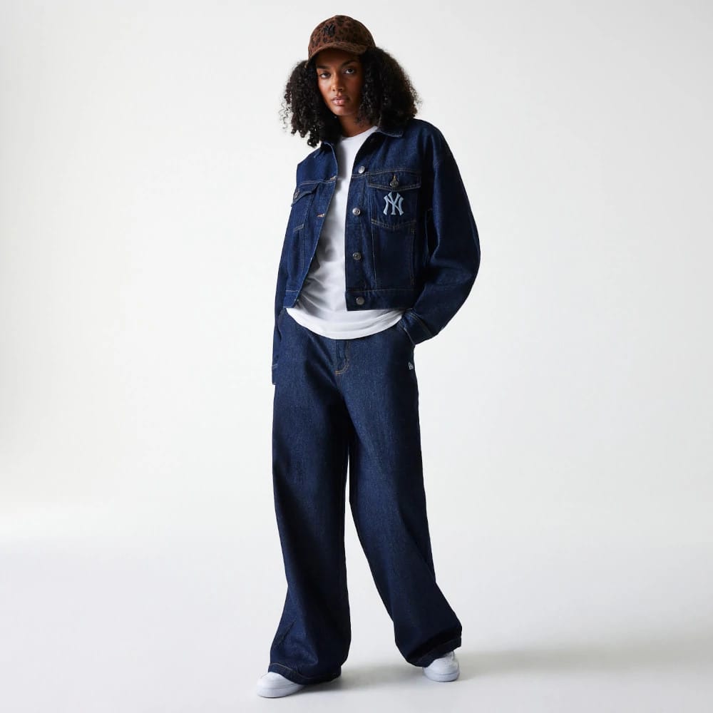New Era New York Yankees Womens MLB Denim Dark Blue Jacket, on-model view showing a dark blue denim jacket with buttons, white embroidered New York Yankees logo on the chest, paired with matching denim trousers and a leopard print cap.