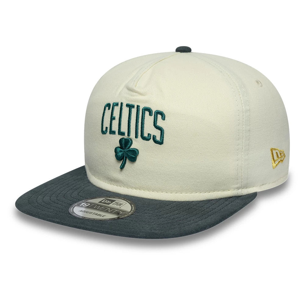 Boston Celtics NBA Metallic Logo Cream New Era 19TWENTY Adjustable Cap, three-quarter view showing the green Celtics lettering and clover emblem embroidered on the cream front panels, a grey visor with a 19TWENTY size sticker.