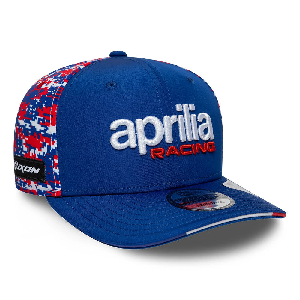 Aprilia Replica Le Mans Race Special Blue New Era 9SEVENTY Stretch Snap Adjustable Cap, three-quarter view showing the raised white and red Aprilia Racing embroidery on the front panel, digital camo print on the side.