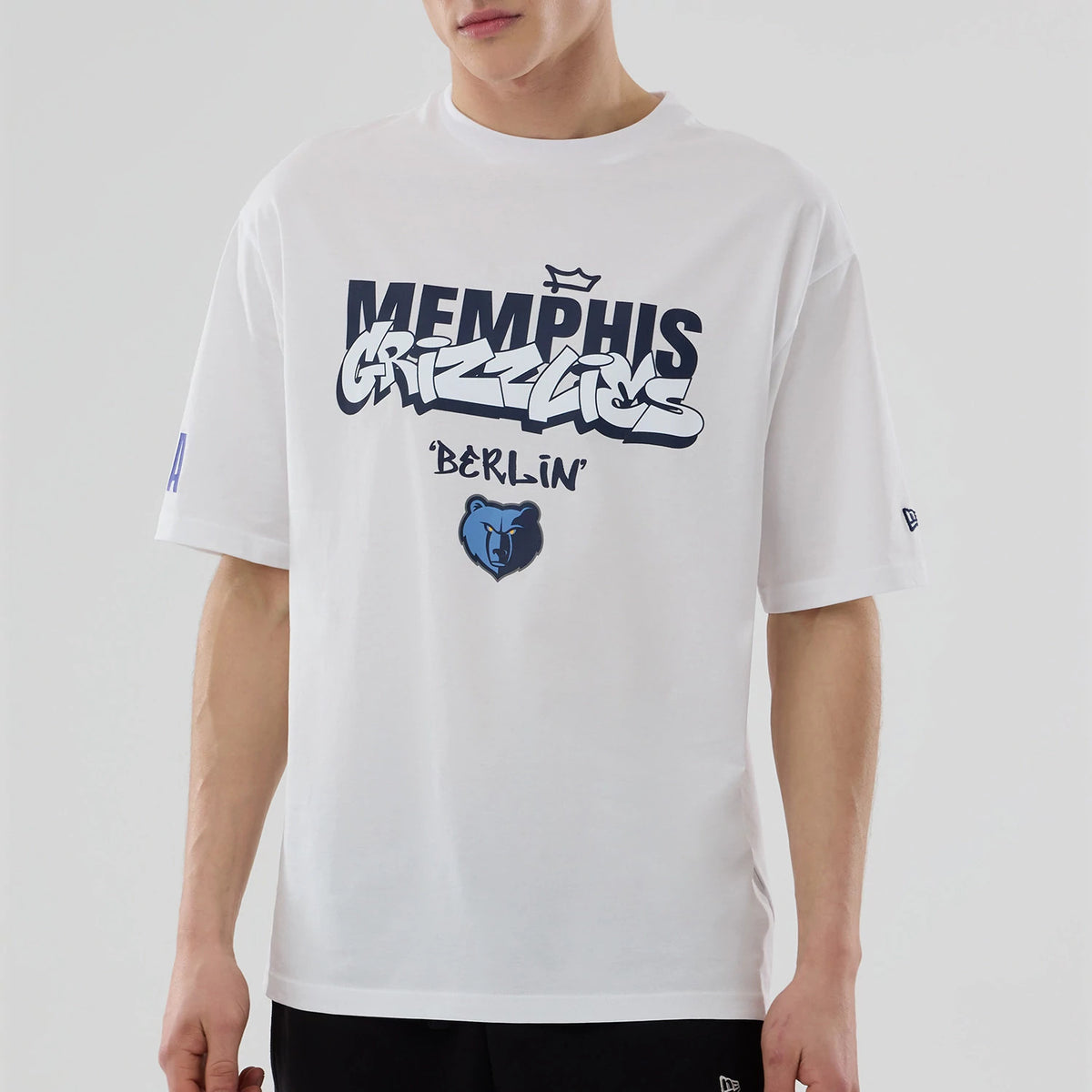 New Era Memphis Grizzlies NBA Berlin Game 2026 White Oversized T-Shirt, front view on model featuring navy Memphis Grizzlies lettering with a crowned graphic and Berlin text beneath, a blue bear logo centred.