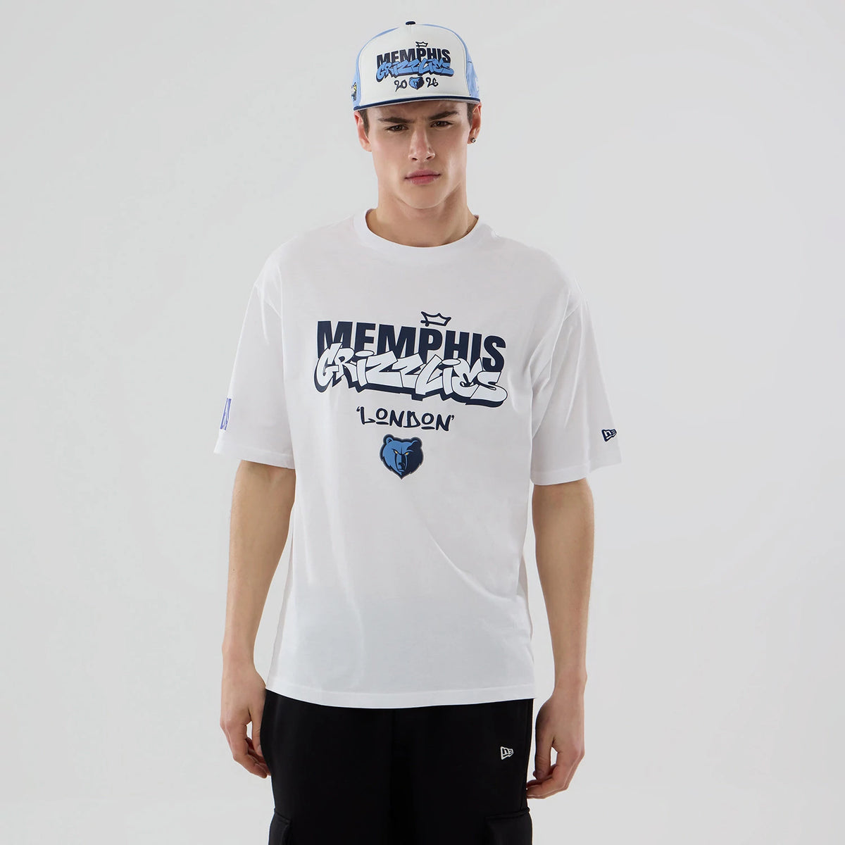 New Era Memphis Grizzlies NBA London Game 2026 White Oversized T-Shirt, front view on a model showcasing navy Memphis Grizzlies lettering, a blue bear logo underneath, and an embroidered New Era logo on the left sleeve.