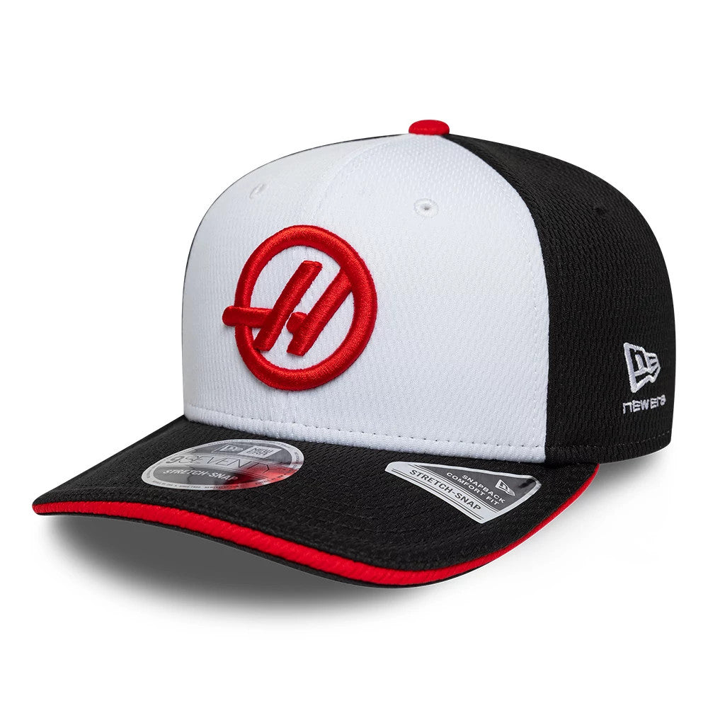 TGR Haas F1 Team Black New Era 9SEVENTY Stretch Snap Adjustable Cap, front view showing a red embroidered team logo on the white front panel, contrasted with a black visor featuring a red rim and a 9SEVENTY size sticker on top.