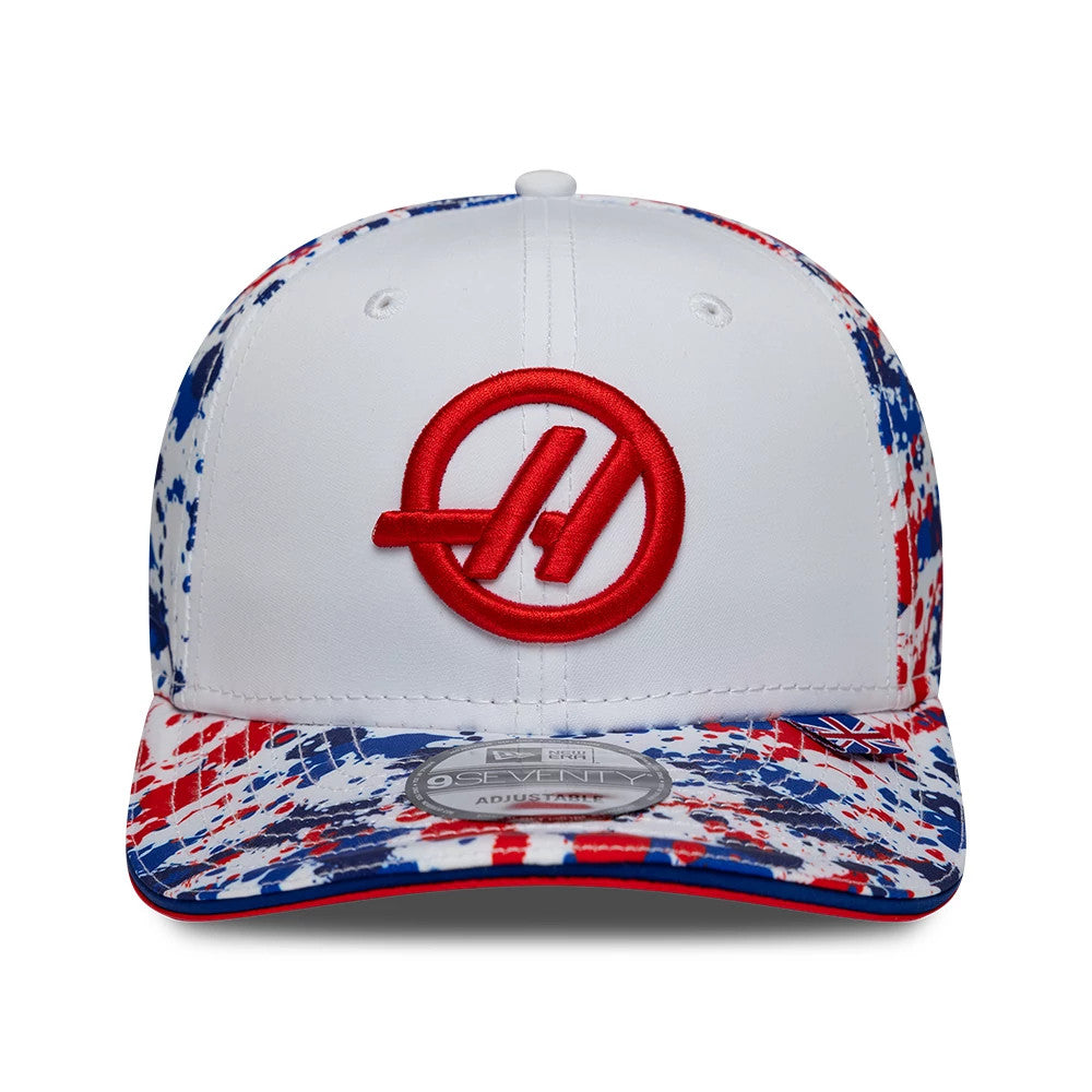 TGR Haas F1 Team Silverstone Race Special White New Era 9SEVENTY Stretch Snap Cap, front view showing prominent red embroidered Haas logo on white crown, a multicolour splatter design on the visor, and 9SEVENTY size sticker centrally placed.