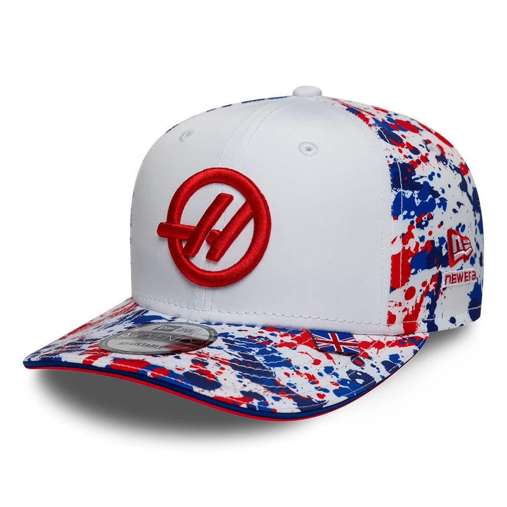 TGR Haas F1 Team Silverstone Race Special White New Era 9SEVENTY Stretch Snap Cap, front view showing a raised red embroidered team logo on the white front panels, with a splattered red, white and blue design on the visor and side panels.