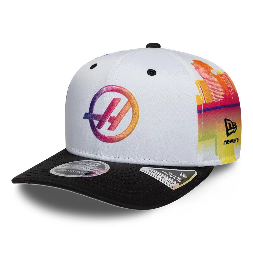 TGR Haas F1 Miami Race Special White New Era 9SEVENTY Stretch Snap Cap, three-quarter view showing a gradient colourful logo on the front panel, a skyline graphic on the side, and a black visor with a 9SEVENTY size sticker.