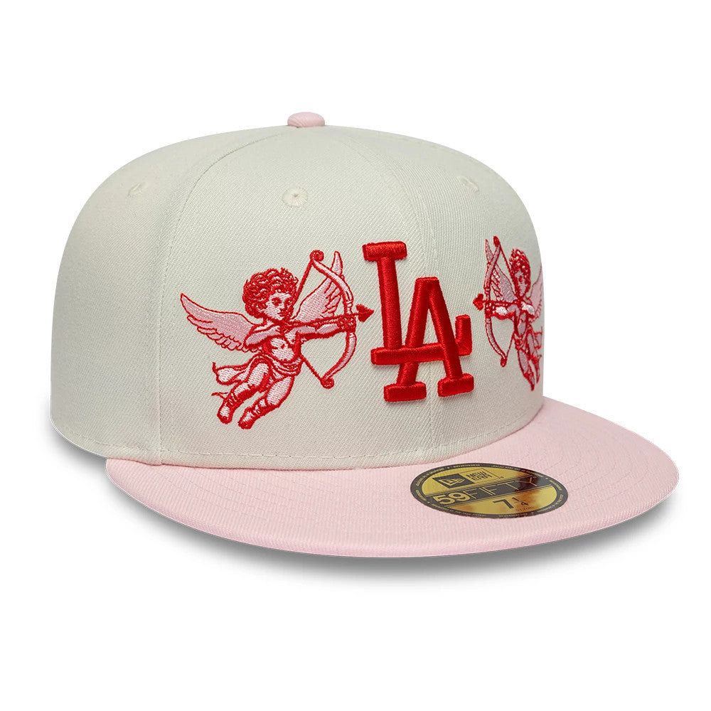 LA Dodgers MLB Cherub Cream & Pink New Era 59FIFTY Fitted Cap, front view showing the red embroidered LA logo on the cream crown with cherub graphics on either side, pink flat visor and the gold 59FIFTY size sticker.