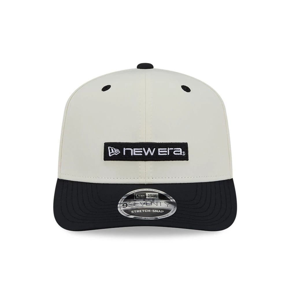 New Era Linear Logo White & Black 9SEVENTY Stretch Snap Adjustable Cap, front view showing a black and white embroidered New Era logo patch on the centre of the structured white crown, with a curved black visor and 9SEVENTY size sticker.
