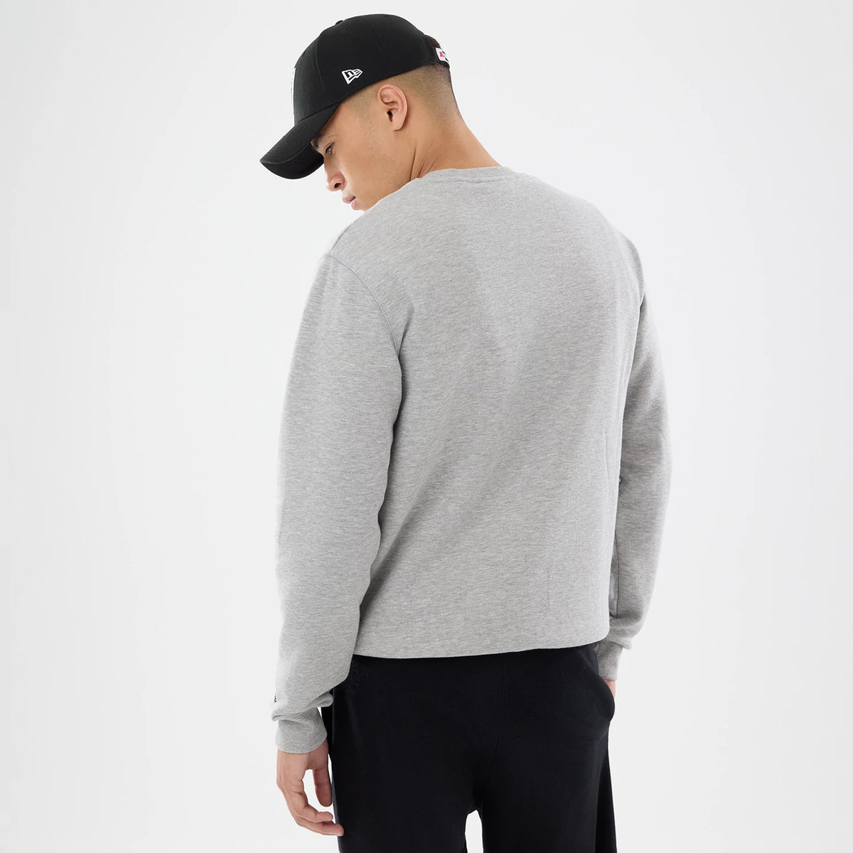 New Era Las Vegas Raiders NFL Training 2026 Grey Crew Neck Sweater, back view on a model wearing a black cap, showing the plain grey back panel, ribbed cuffs and relaxed fit, with a long sleeve design for a casual look.
