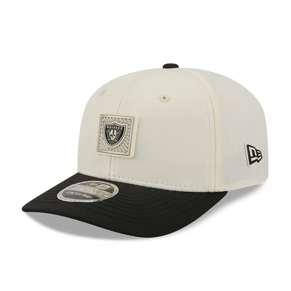 Raiders NFL Training 2026 White New Era 9SEVENTY Stretch Snap Adjustable Cap, three-quarter view showing the raised Raiders badge on the white front panel, a black curved visor with a 9SEVENTY size sticker, and the New Era flag logo on the left side.