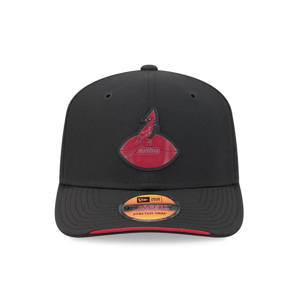 Cardinals NFL Sideline 2026 Black New Era 9SEVENTY Stretch Snap Adjustable Cap, front view showing the raised cardinal logo embroidered on the black front panel, black curved visor with a contrasting red undervisor, and 9SEVENTY size sticker.