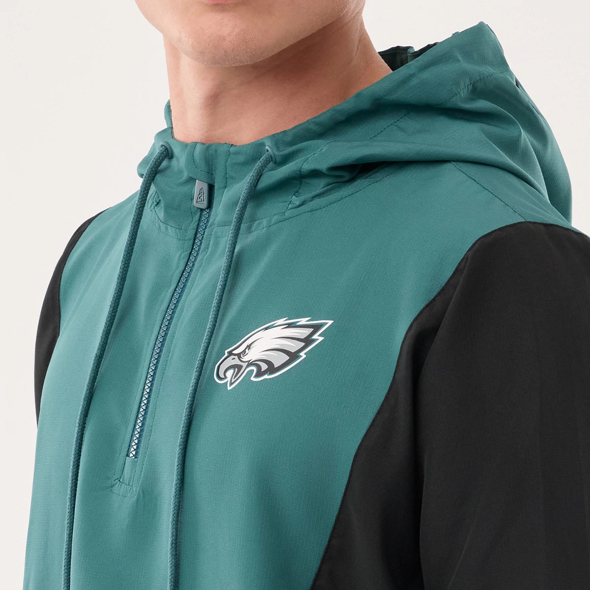 New Era Philadelphia Eagles NFL Dark Green Jacket, front view showing the contrast between the dark green body and black sleeves, with an embroidered team logo on the left chest, a drawstring hood, and a partially zipper under the chin.