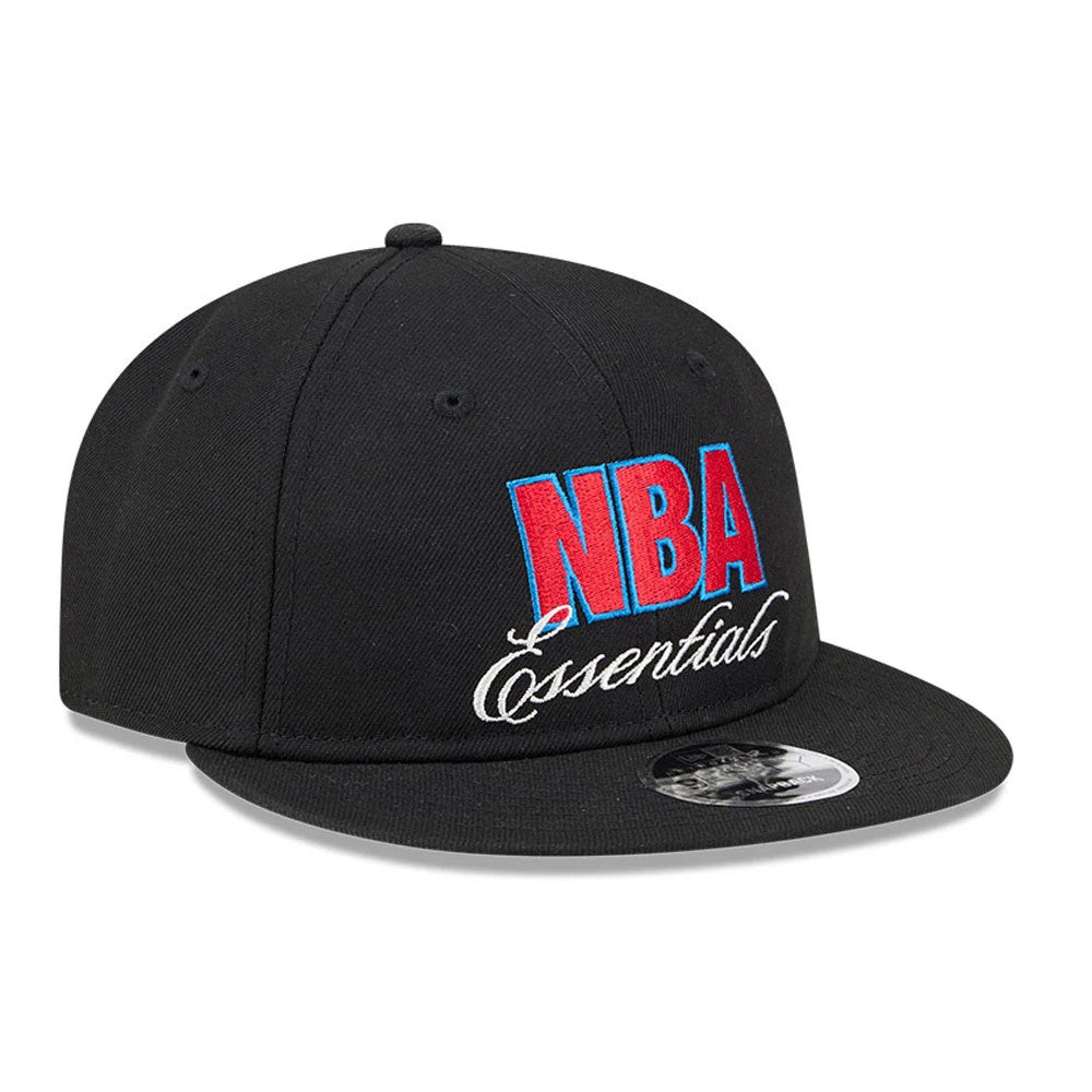 FOG x NBA Logo Black Retro Crown New Era 9FIFTY Snapback Adjustable Cap, three-quarter view showing the red and blue NBA Essentials embroidery on the front panel, matching flat black visor, and silver 9FIFTY size sticker on the visor.