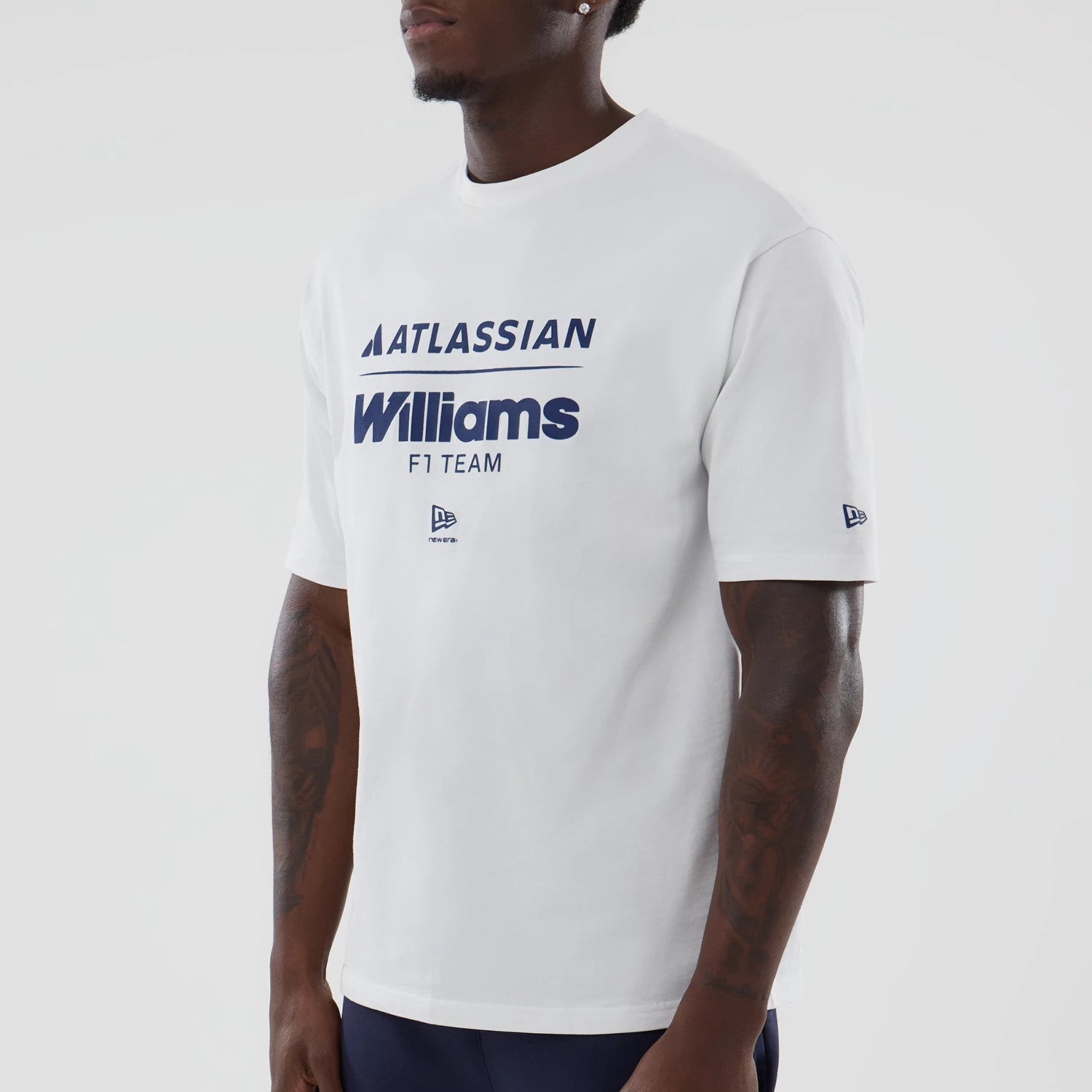 New Era Williams White Oversized T-Shirt, front view on a model showing blue Atlassian Williams F1 Team lettering across the chest, a small New Era embroidered logo beneath, and an additional New Era logo on the left sleeve.