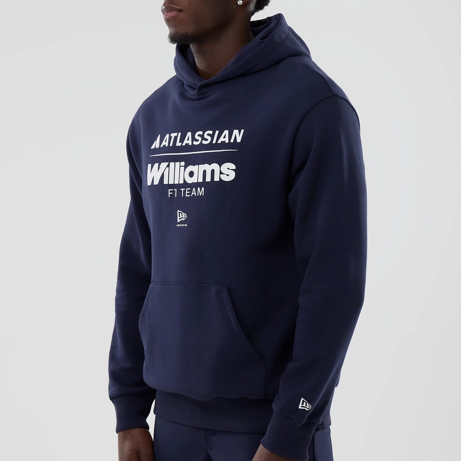 New Era Williams Navy Oversized Pullover Hoodie, front view on-model displaying white printed Williams F1 team graphics on the chest, New Era logo embroidered on the pocket, and another embroidered logo on the sleeve cuff.