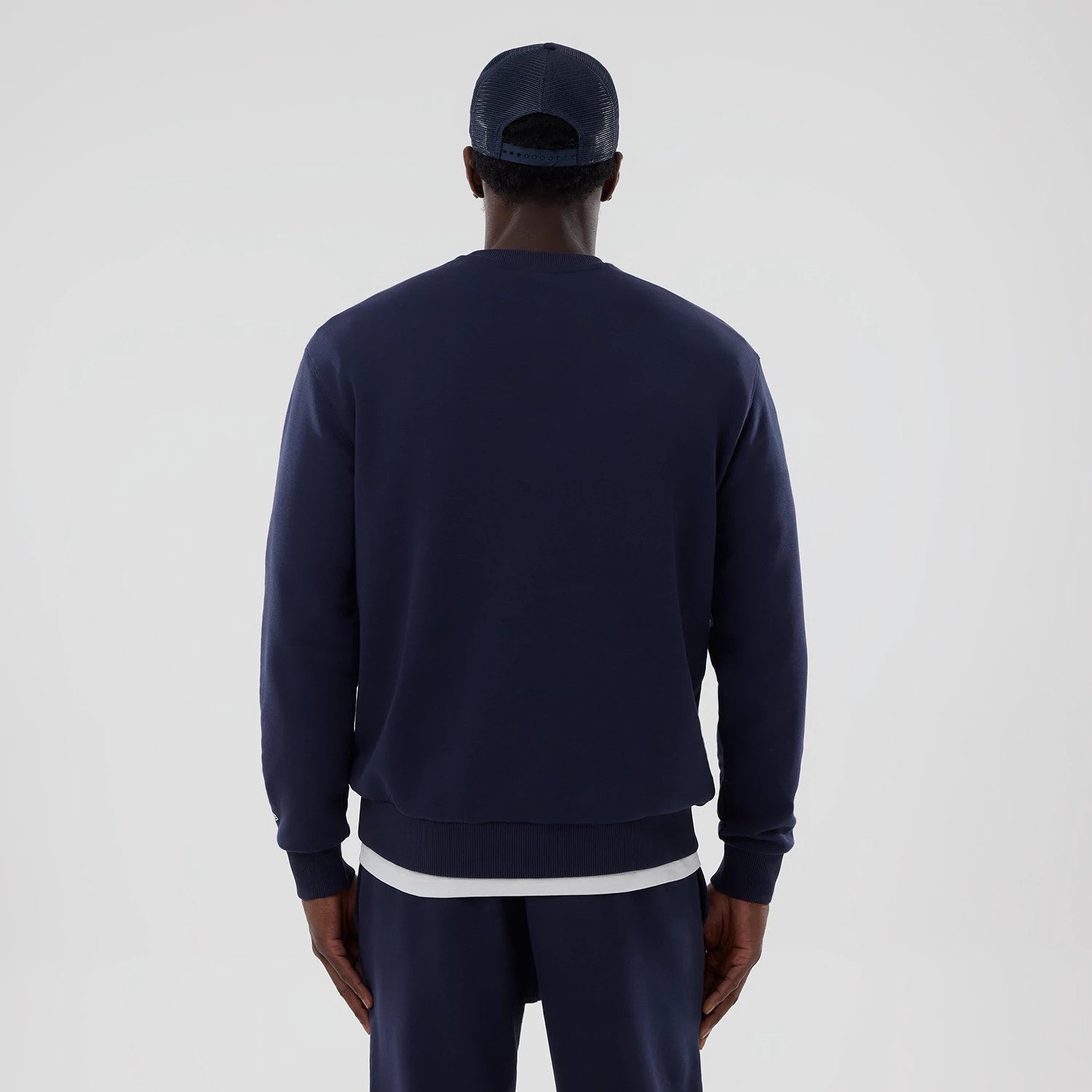 New Era Williams Navy Oversized Crewneck Sweater, back view on a model displaying the slightly dropped shoulder seams, ribbed cuffs and hem, with contrasting white inner shirt detail at the waist.