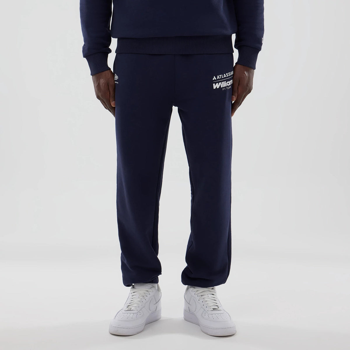 New Era Williams Navy Joggers, front view on a model wearing white trainers, showing the white Williams F1 Team and Atlassian logos on the right thigh, and the small white New Era flag logo on the left hip.