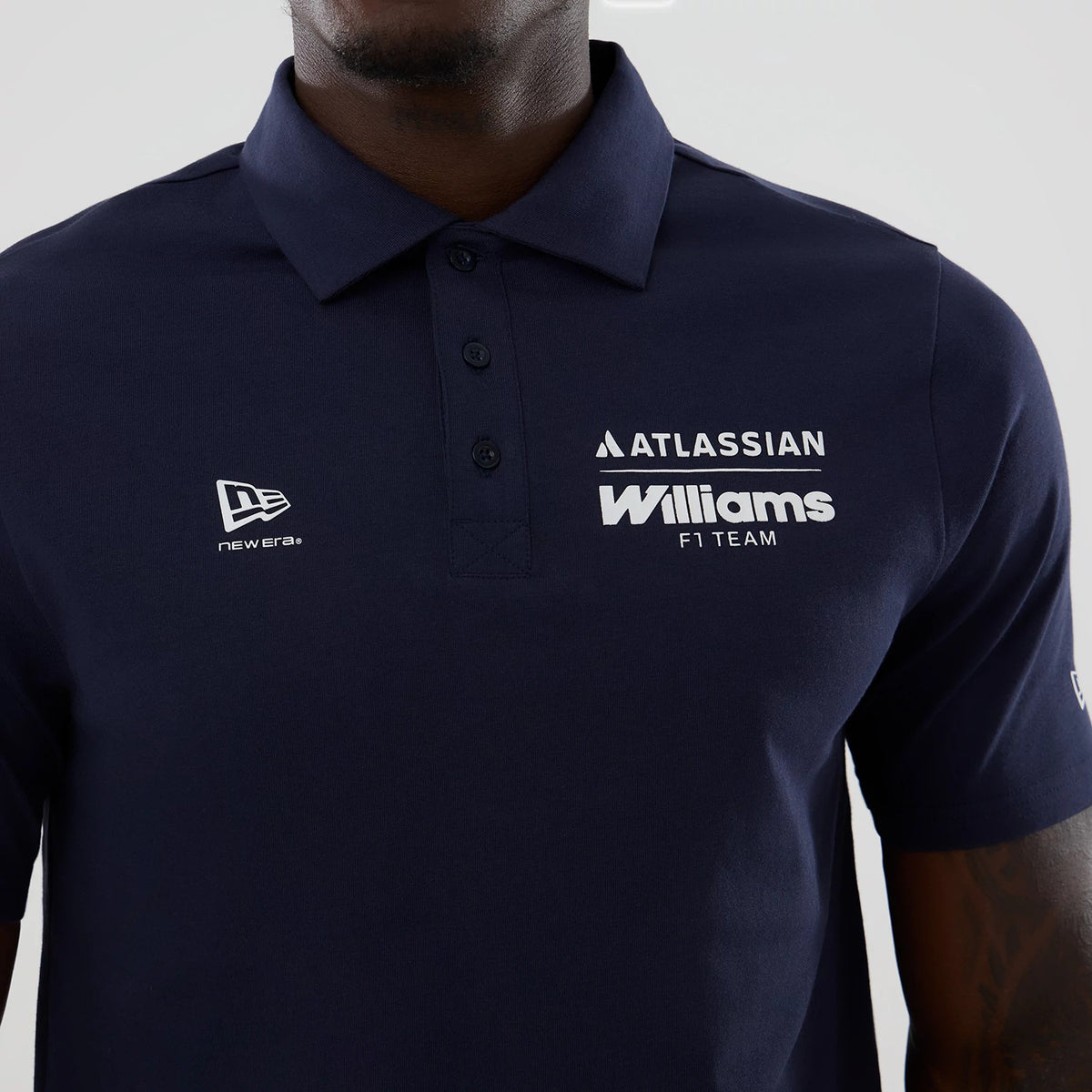 New Era Williams Navy Polo T-Shirt, front view showing the dark blue colour with a three-button placket, an embroidered New Era logo on the left chest, and white printed Williams F1 Team and Atlassian branding on the right chest.