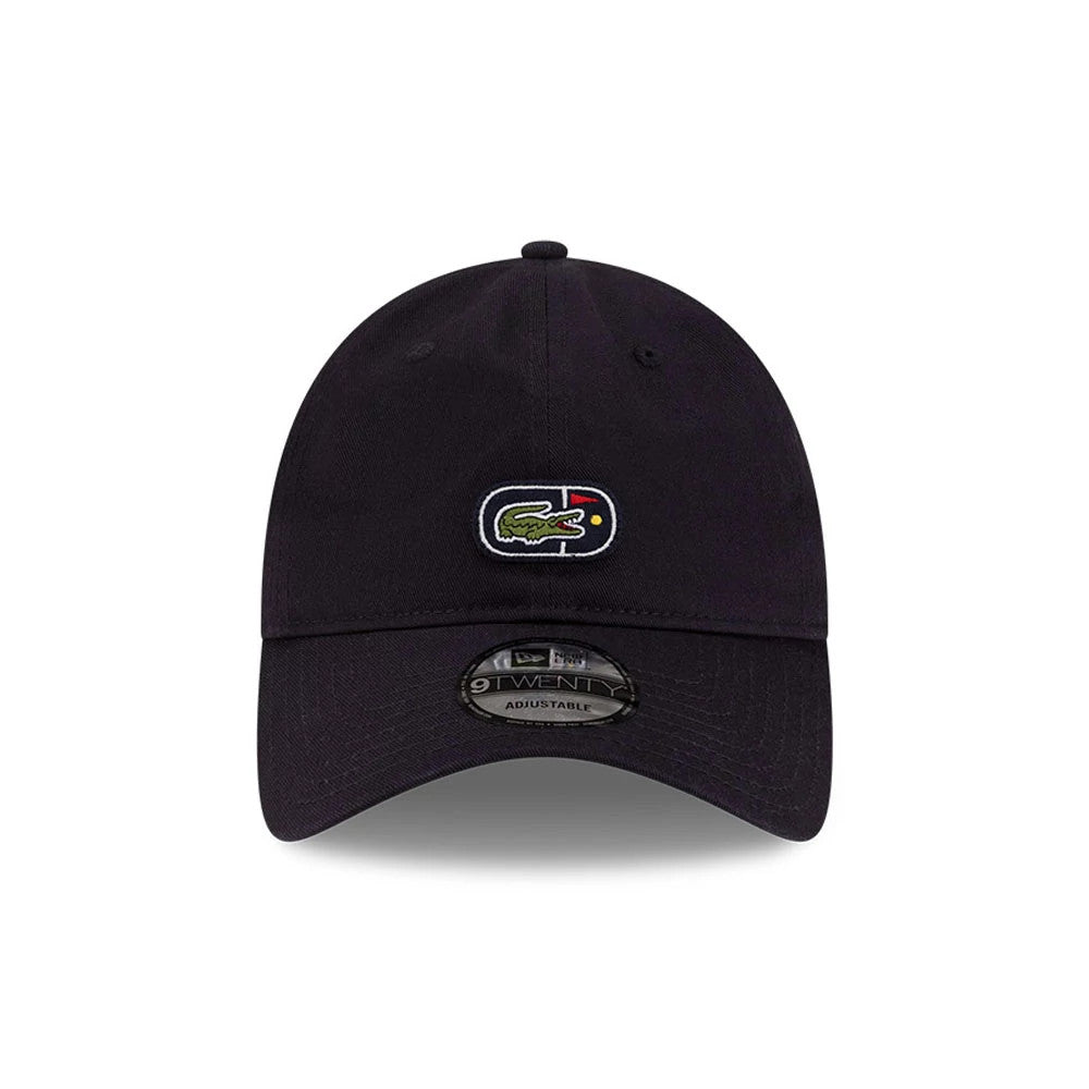 Lacoste X New Era Navy 9TWENTY Adjustable Cap, front view showing the embroidered Lacoste crocodile logo centred on the unstructured navy crown with eyelets, a curved visor, and a 9TWENTY size sticker on the dark undervisor.