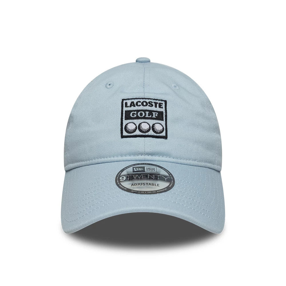 Lacoste X New Era Pastel Blue 9TWENTY Adjustable Cap, front view showing the black and white embroidered Lacoste Golf logo on the front panel, with a curved pastel blue visor and the 9TWENTY size sticker prominently displayed on the centre.