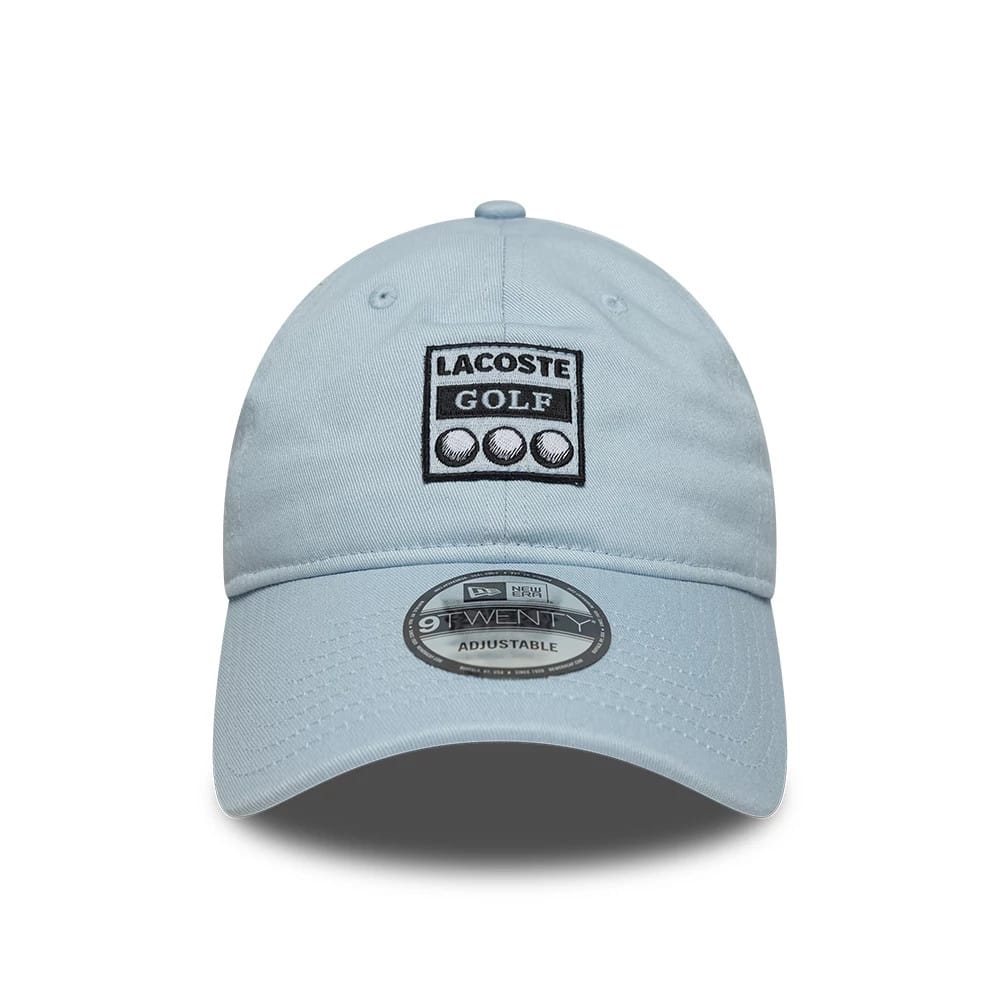 Lacoste X New Era Pastel Blue 9TWENTY Adjustable Cap, front view showing the black and white embroidered Lacoste Golf logo on the front panel, with a curved pastel blue visor and the 9TWENTY size sticker prominently displayed on the centre.
