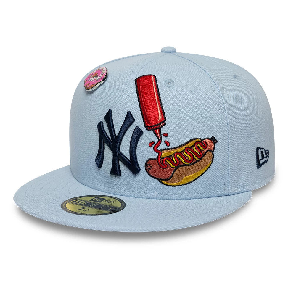 New York Yankees MLB Food Pastel Blue New Era 59FIFTY Fitted Cap, front view showing a navy NY logo with a red and yellow hot dog and sauce embroidery, a pink doughnut pin on the crown, and a gold 59FIFTY size sticker on the blue visor.