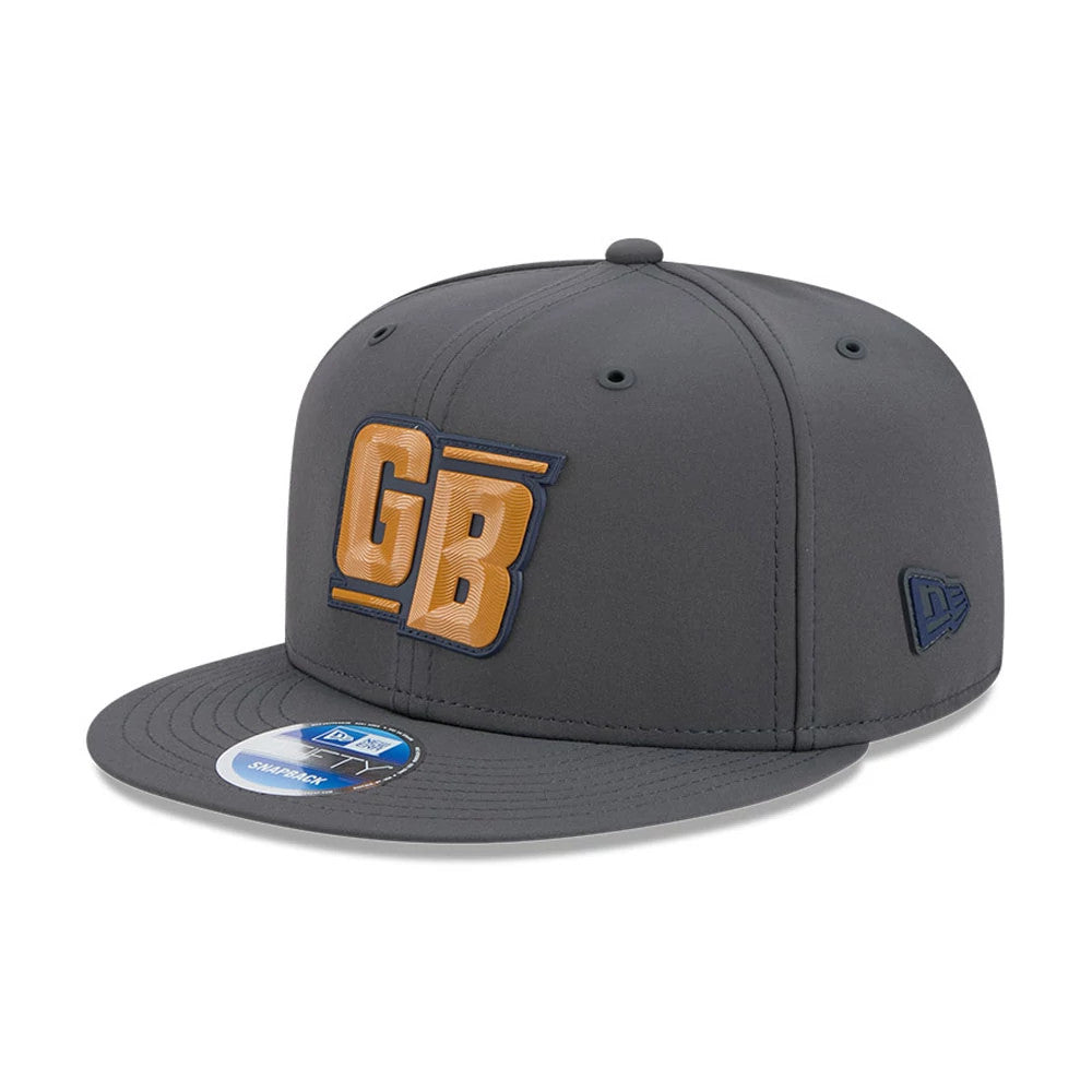 Packers NFL Sideline 2026 Charcoal New Era 9FIFTY Snapback Adjustable Cap, three-quarter view showing a raised embroidered GB logo in gold with blue outline on the front panel, a blue New Era flag logo on the left side.