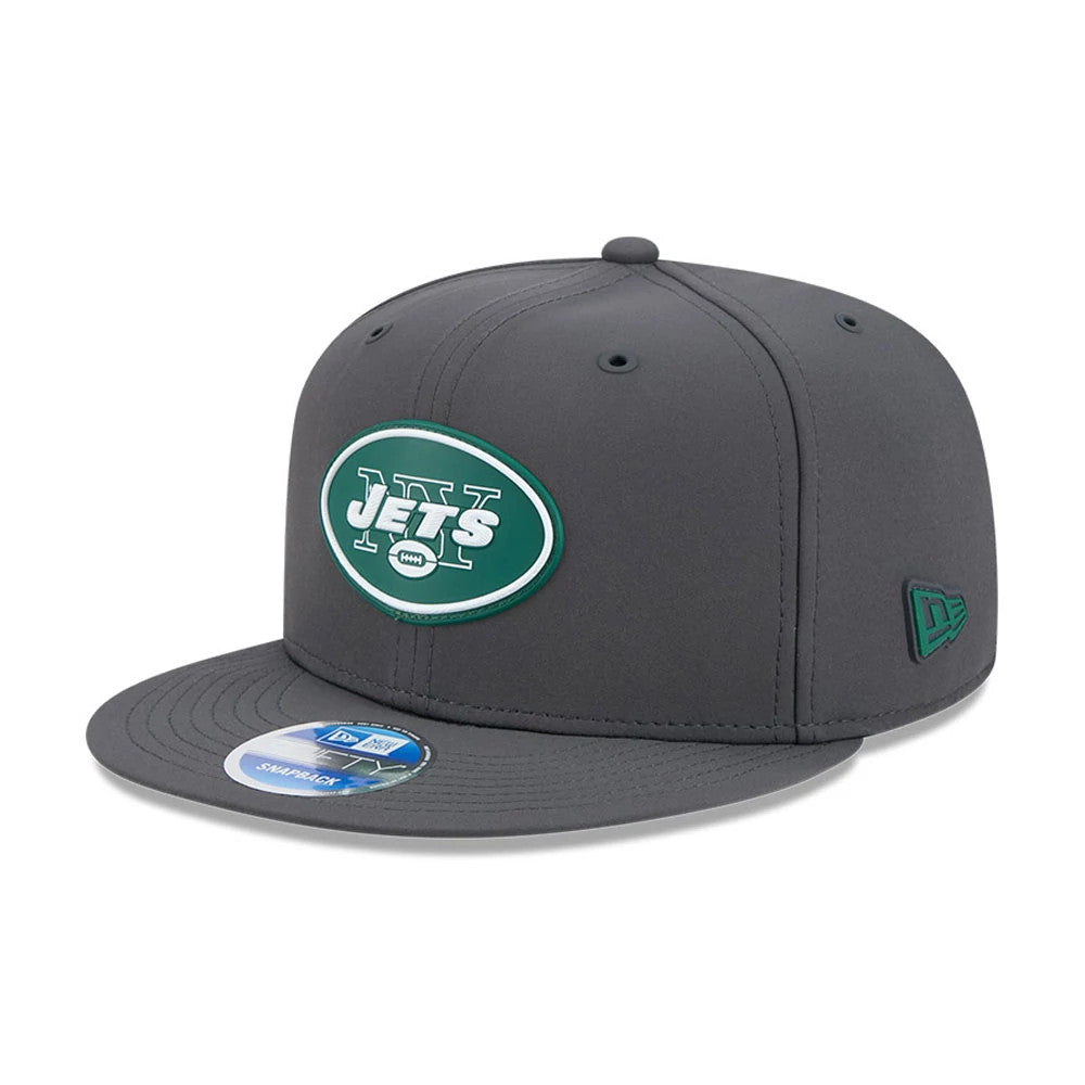 New York Jets NFL Sideline 2026 Charcoal New Era 9FIFTY Snapback Adjustable Cap, three-quarter view showing a green and white Jets logo with raised embroidery on the front panel, charcoal grey flat visor and New Era flag logo on the left side.