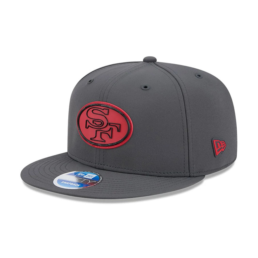 49ers NFL Sideline 2026 Charcoal New Era 9FIFTY Snapback Adjustable Cap, three-quarter view showing a red SF logo outlined in black on the front panel, black New Era flag logo on the left side, and a 9FIFTY size sticker on the visor.