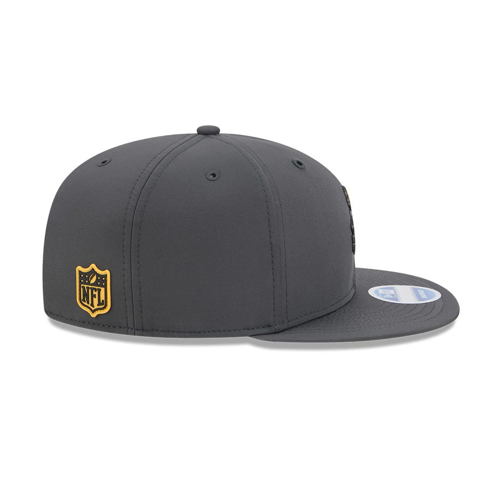 Steelers NFL Sideline 2026 Charcoal New Era 9FIFTY Snapback Adjustable Cap, side view showing the raised embroidery NFL logo in gold on the back panel, with a flat charcoal visor and 9FIFTY size sticker on the visor.