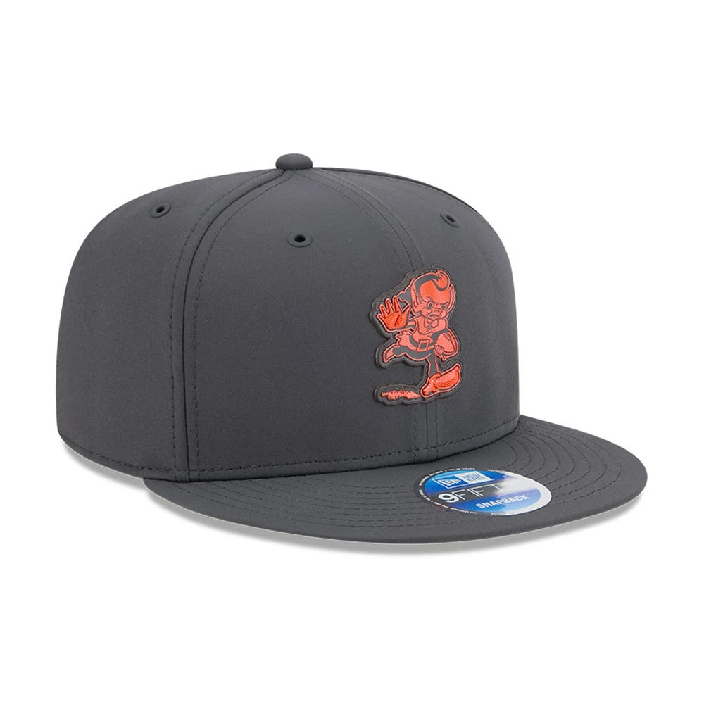 Browns NFL Sideline 2026 Charcoal New Era 9FIFTY Snapback Adjustable Cap, three-quarter view showing a front panel with an orange embroidered logo, a flat charcoal visor, and a 9FIFTY size sticker on the visor.