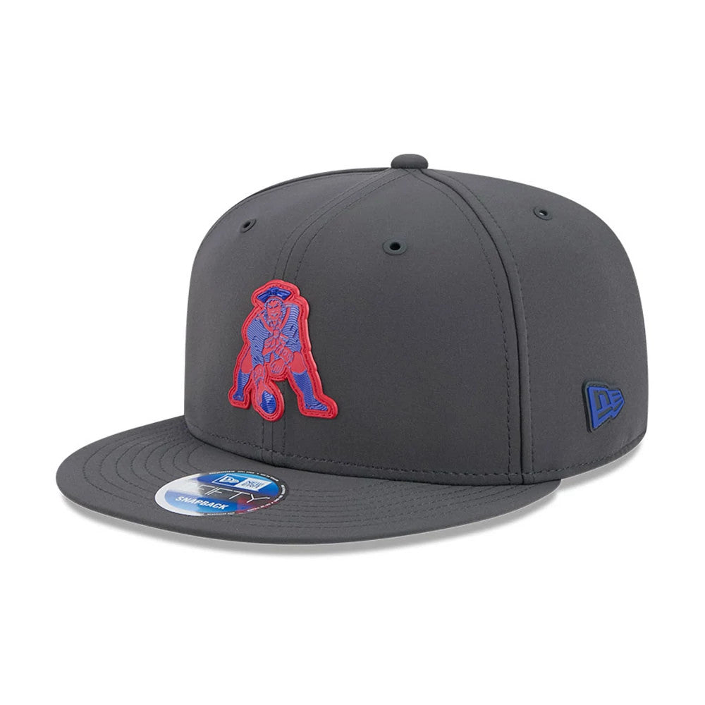 Patriots NFL Sideline 2026 Charcoal New Era 9FIFTY Snapback Adjustable Cap, three-quarter view showing the raised red and blue embroidered Patriots logo on the front panel, charcoal flat visor with the 9FIFTY size sticker.