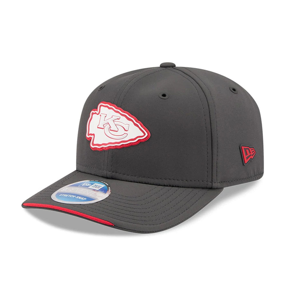 Chiefs NFL Sideline 2026 Charcoal New Era 9SEVENTY Stretch Snap Adjustable Cap, three-quarter view showing the white and red embroidered team logo on the front panel, charcoal curved visor with a red edge, and navy 9SEVENTY size sticker.