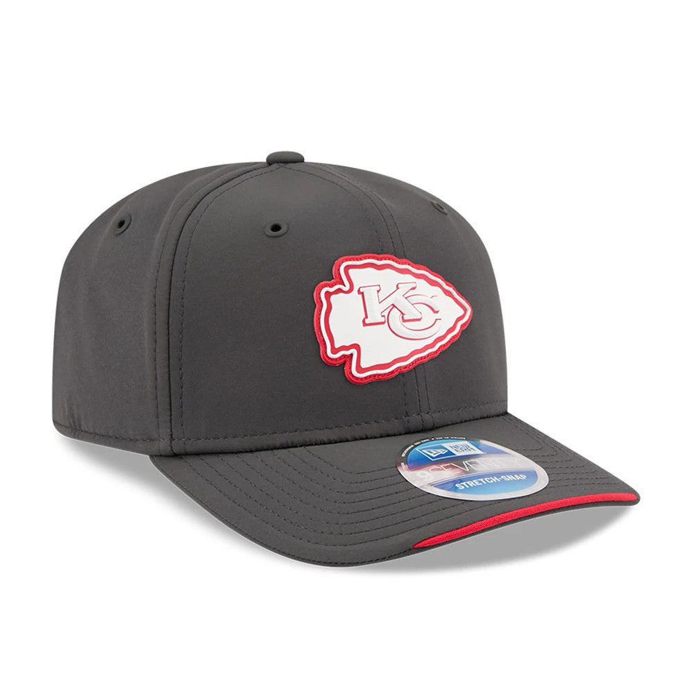 Chiefs NFL Sideline 2026 Charcoal New Era 9SEVENTY Stretch Snap Adjustable Cap, three-quarter view showing the raised Chiefs arrowhead logo embroidered on the front panel, dark charcoal curved visor with a red edge, and a 9SEVENTY size sticker.