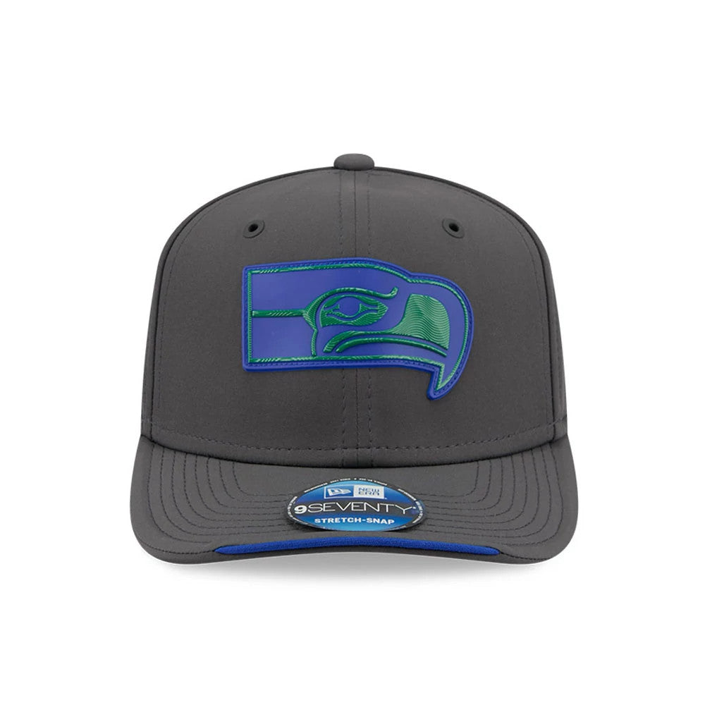 Seahawks NFL Sideline 2026 Charcoal New Era 9SEVENTY Stretch Snap Adjustable Cap, front view showing a blue and green embroidered Seahawks logo on the structured charcoal crown, a curved charcoal visor, and the 9SEVENTY size sticker.