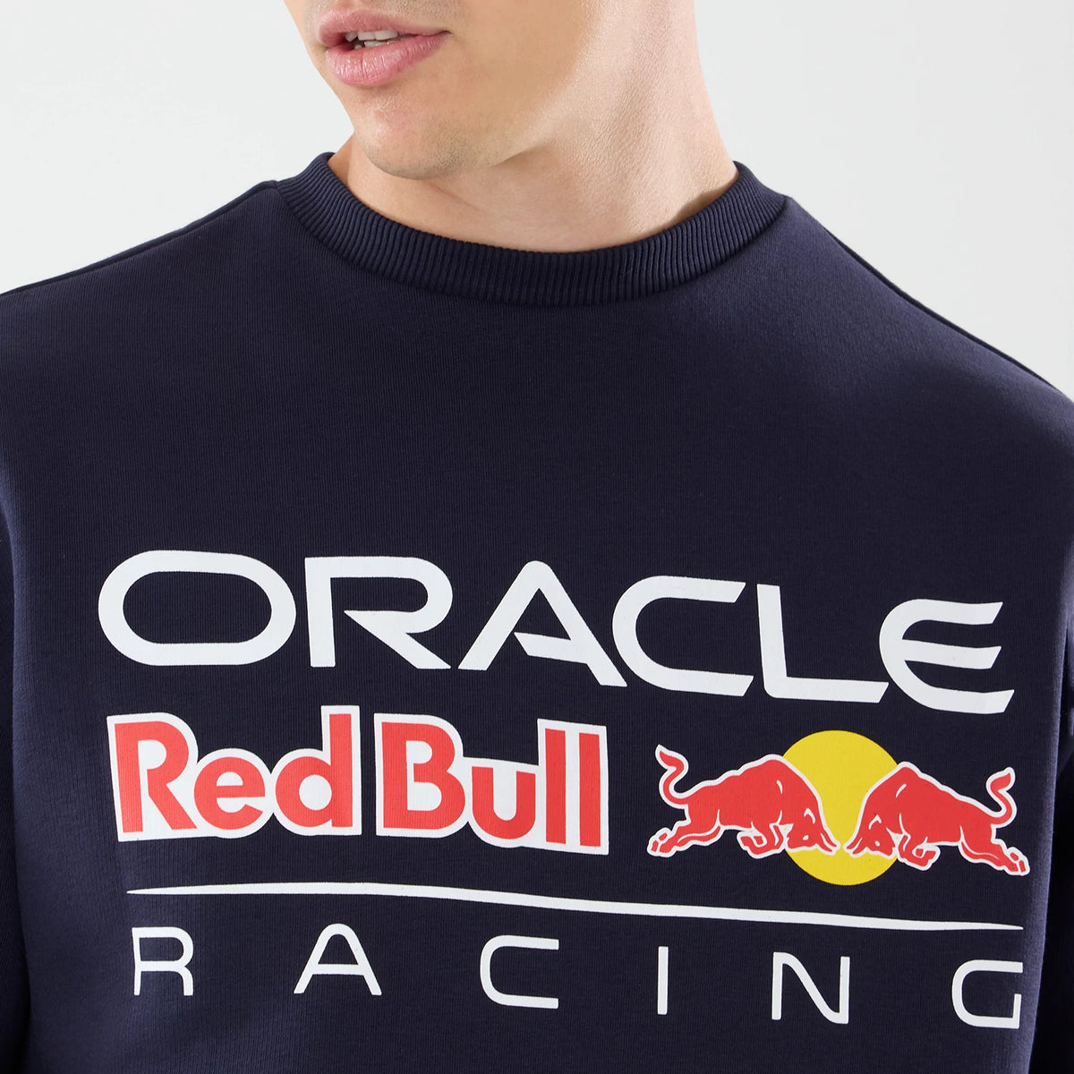New Era Red Bull Racing Dark Blue Oversized Crew Neck Sweater, front view on a model showing the large, prominently printed ORACLE Red Bull Racing logo in white and red across the chest, with a vivid yellow circle and red bull graphics.