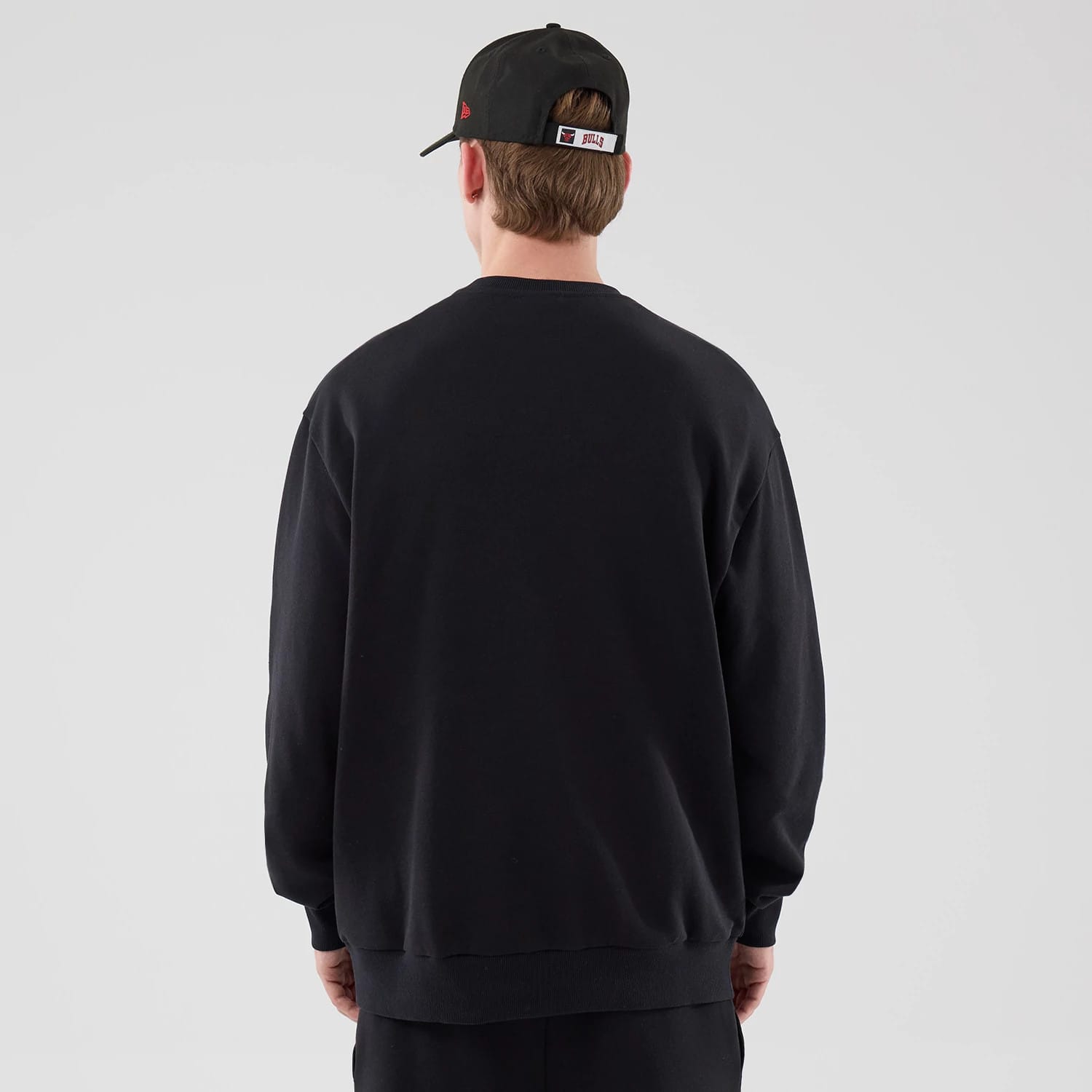 The model is wearing this NBA League Essential Chicago Bulls Oversized Crew Neck Sweater in black. 2