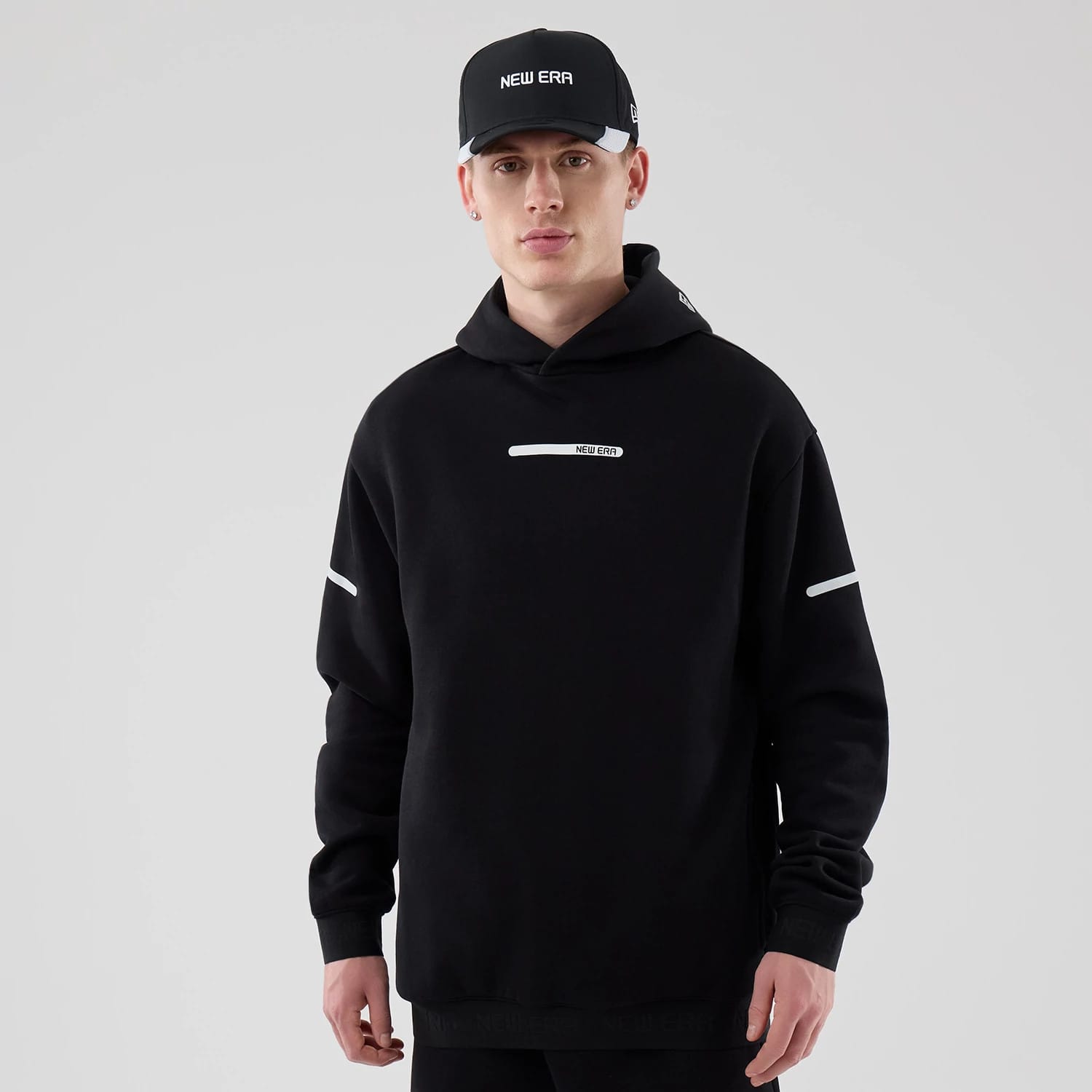 The model is wearing this New Era Tech Oversized Pullover Hoodie in black. 1