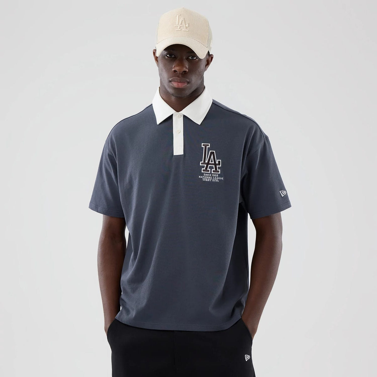 New Era LA Dodgers MLB Grey Polo T-Shirt, front view on a model showcasing a large white embroidered LA logo on the upper left chest, a contrasting white collar with a buttoned placket, and a small embroidered New Era flag on the left sleeve.