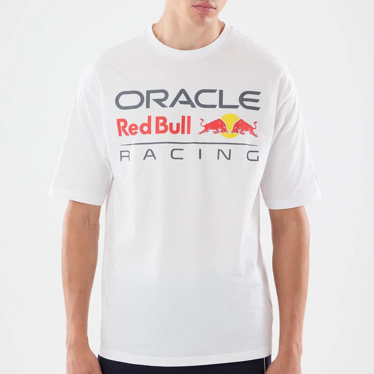New Era Red Bull Racing Graphic White Oversized T-Shirt, front view on a model displaying a printed logo in red, yellow, and grey hues across the chest reading Oracle Red Bull Racing, with short sleeves and a relaxed fit.