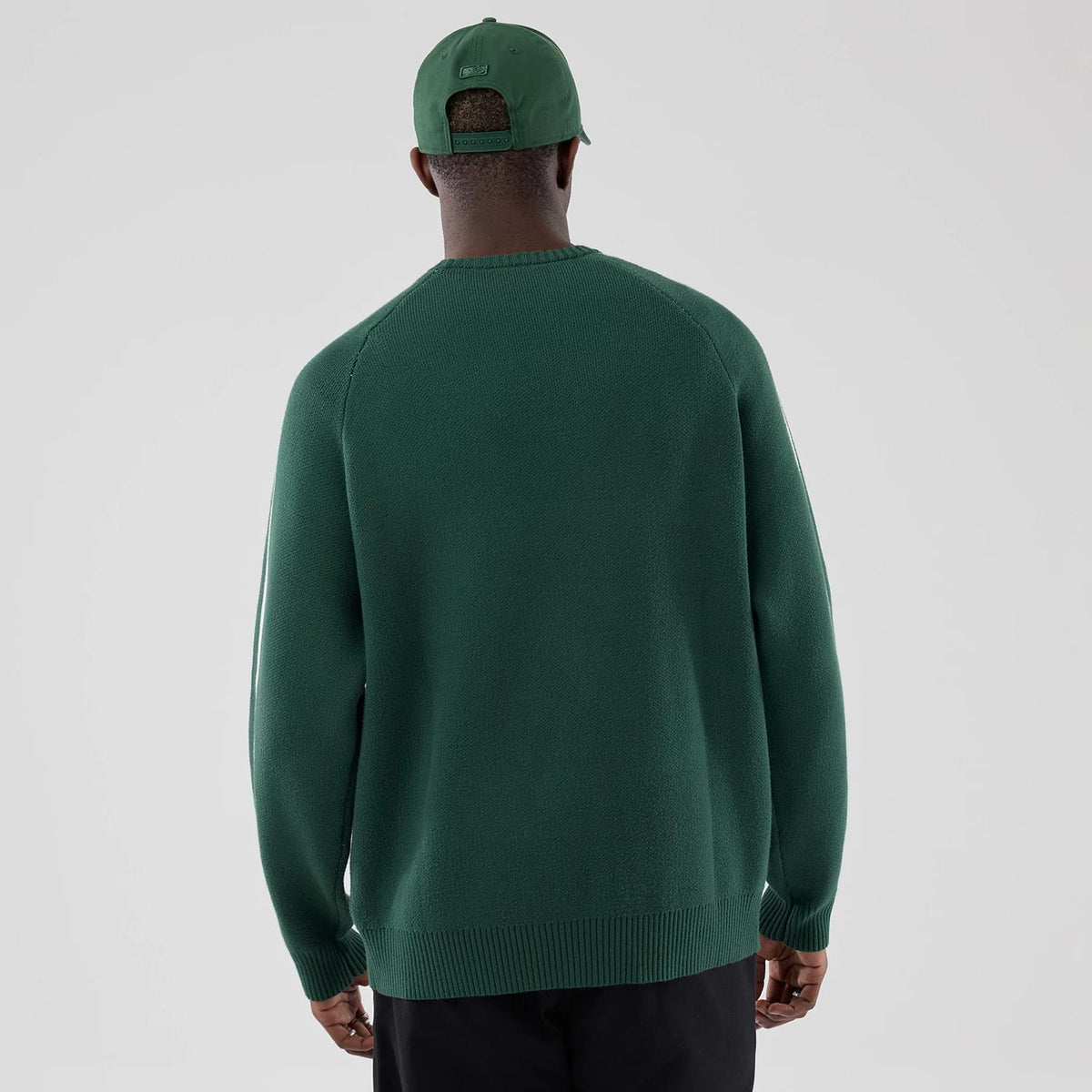 New Era LA Dodgers MLB Knit Dark Green Knitted Sweater, back view on a model wearing a matching dark green cap, showing the ribbed neckline, long sleeves with seams, and a straight hem that falls at the waist.