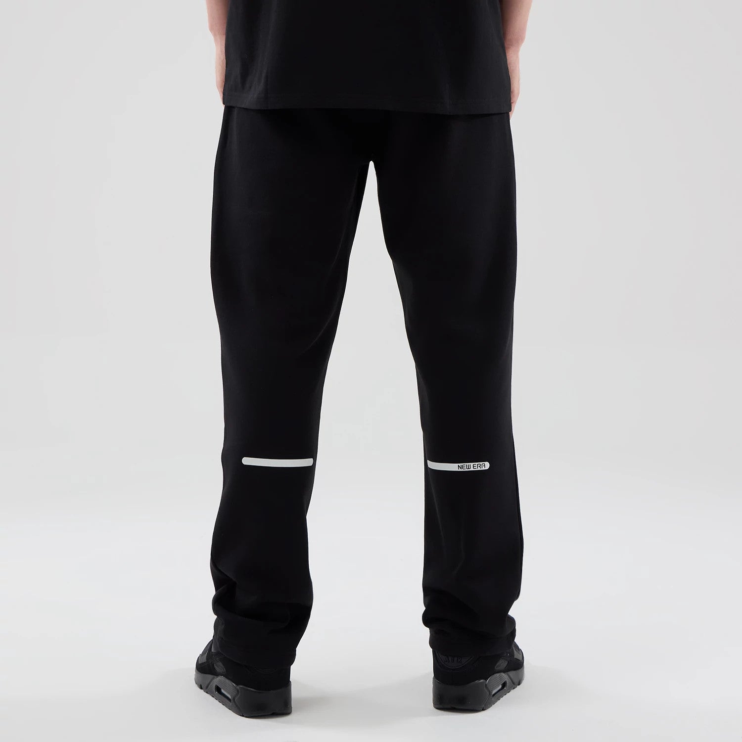 The model is wearing these New Era Tech Reflective Straight Leg Joggers in black. 2