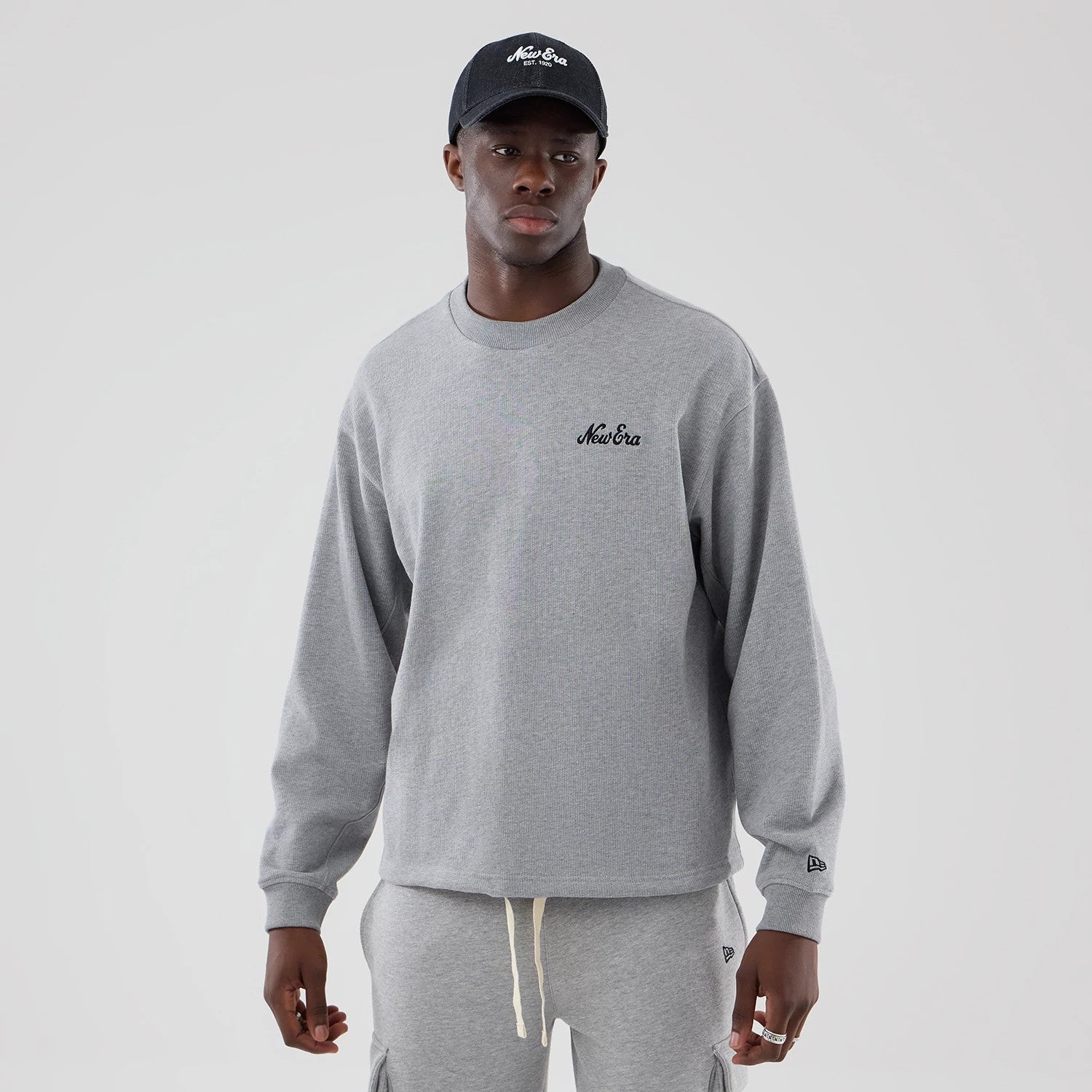 The model is wearing this New Era Oversized Crew Neck Sweater in grey. 1