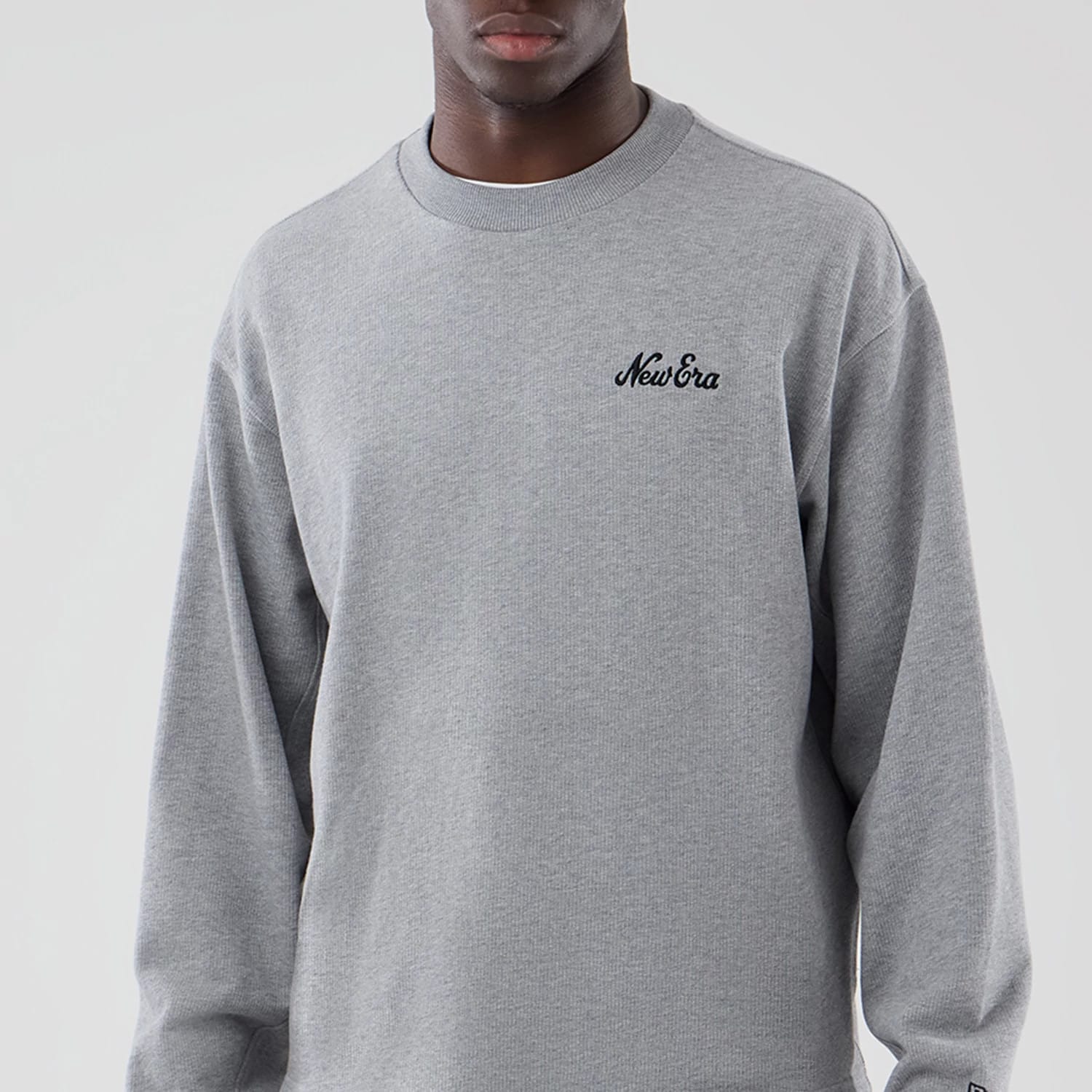 The model is wearing this New Era Oversized Crew Neck Sweater in grey. 3