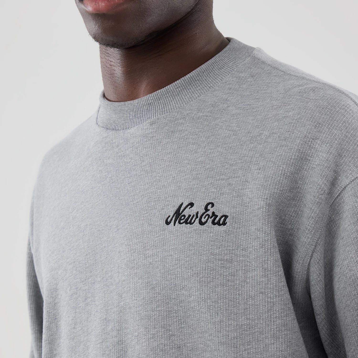 The model is wearing this New Era Oversized Crew Neck Sweater in grey. 4