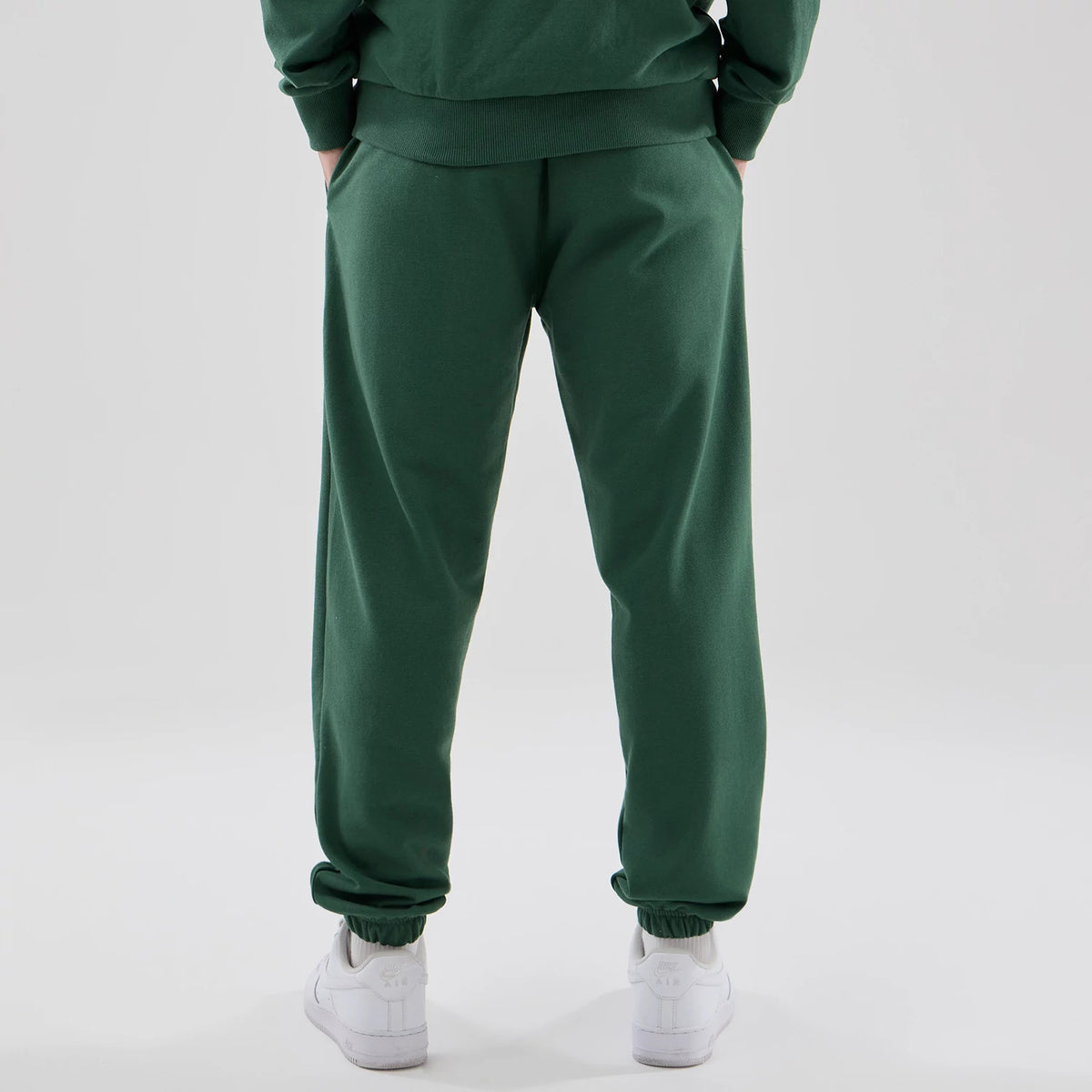 New Era New York Yankees MLB Midi League Essential Dark Green Joggers, back view on a model showing the elasticated cuffs and waistband, slip pockets on each side, with the dark green fabric draping loosely over white trainers.
