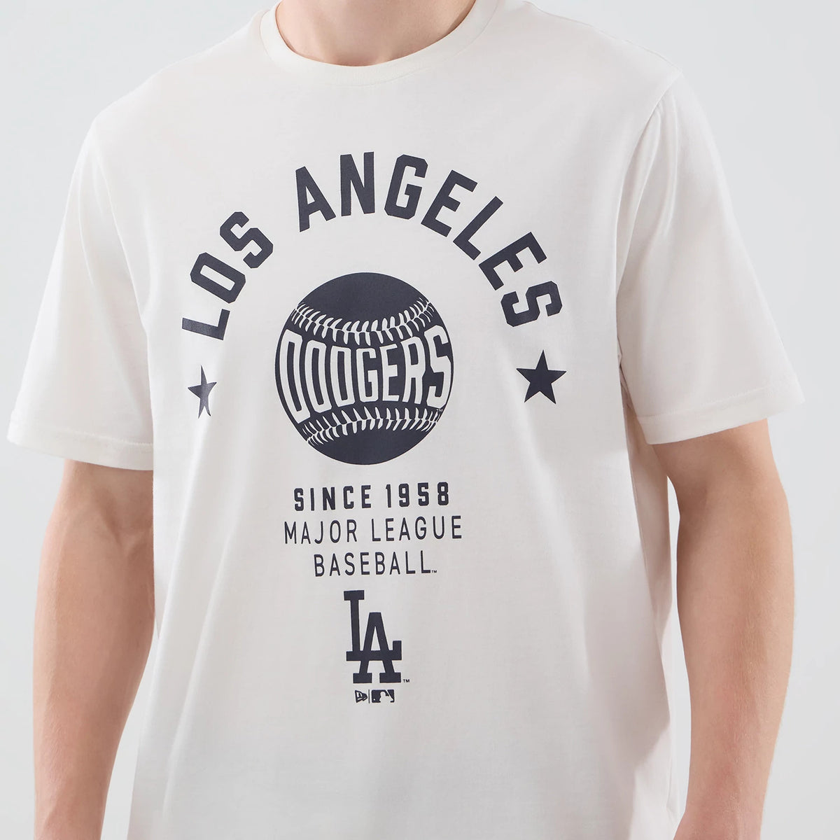 New Era LA Dodgers MLB Graphic Open White T-Shirt, front view on-model displaying black printed lettering arching over a large baseball graphic and Dodgers script, with LA logo and Since 1958 Major League Baseball text beneath.