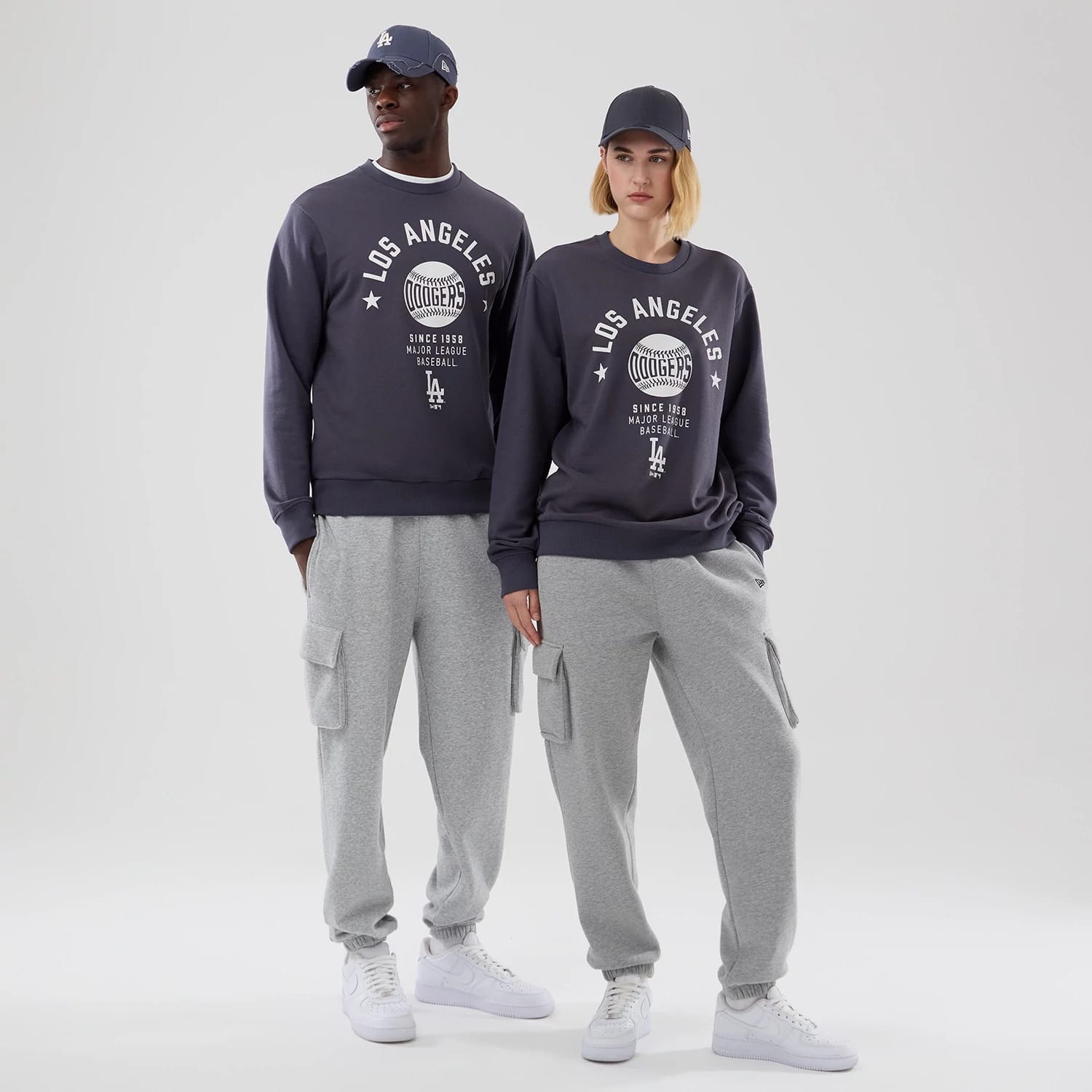 New Era LA Dodgers MLB Graphic Grey Oversized Crew Neck Sweater, front view on a model showcasing a large white Los Angeles Dodgers baseball graphic on the chest, matched with grey cargo joggers and white trainers.